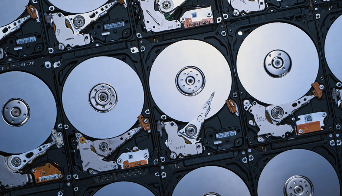 Múltiples discos duros HDD abiertos mostrando platos y actuadores, utilizados como referencia en el análisis sobre rendimiento tipo flash y alto throughput en 2026
